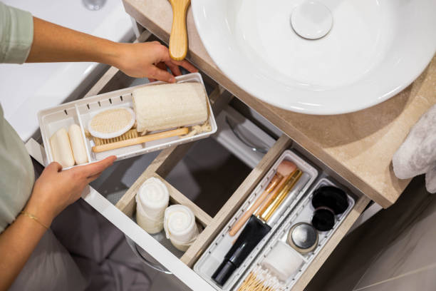Top view of woman hands neatly organizing bathroom amenities and toiletries in drawer in bathroom stock photo