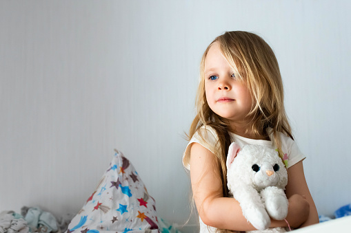 Portrait of a little girl in the children's room hugging a toy. Smiling in the background of the room.