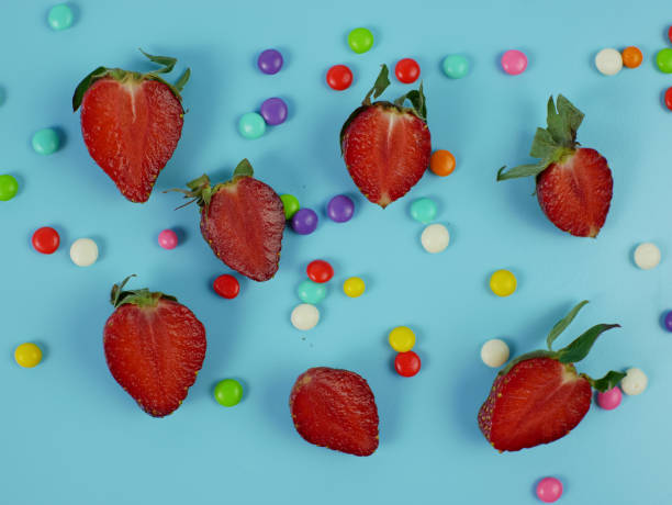 istock sliced fresh strawberries and colorful sweet candy on blue background. flat lay 1367071621