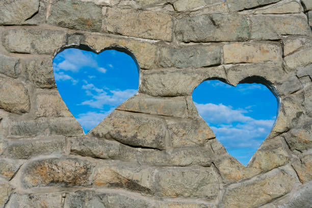 Old brick wall with Two hearts Shaped Hole showing Blue Sky,Valentine.