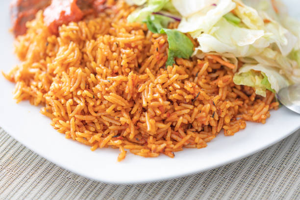 nigerianischer afrikanischer jollof reis serviert mit gemüsesalat - canada rice stock-fotos und bilder