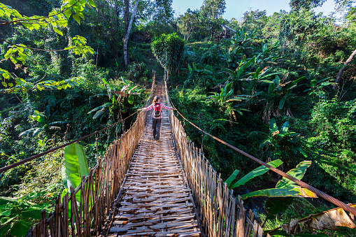 Woman with backpack on suspension bridge in rainforest