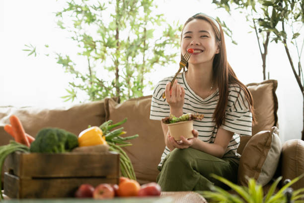 Portrait of an Asian woman with sustainable lifestyle eating salad Portrait of an Asian woman with sustainable lifestyle eating salad EATING stock pictures, royalty-free photos & images