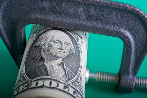 istock Clamp squeezing roll of U.S.  dollar bills 1367082754