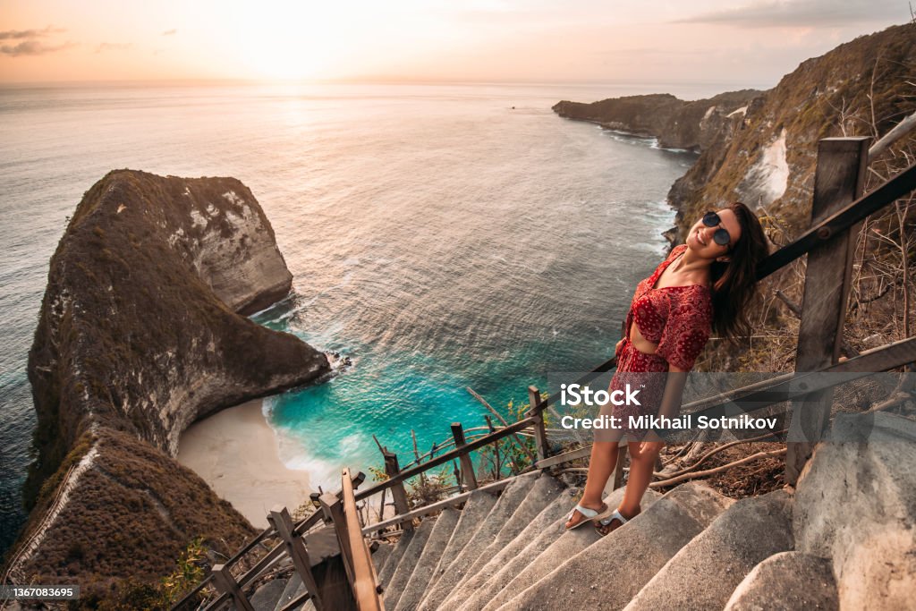 Beautiful girl on the background of Kelingking beach, Nusa Penida Indonesia. A young woman is traveling in Indonesia. Nusa Penida is one of the most famous tourist attraction place to visit in Bali Kelingking Beach Stock Photo
