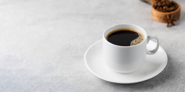 istock Black coffee in a white mug on a saucer on a grey table. Copy space. 1367087771