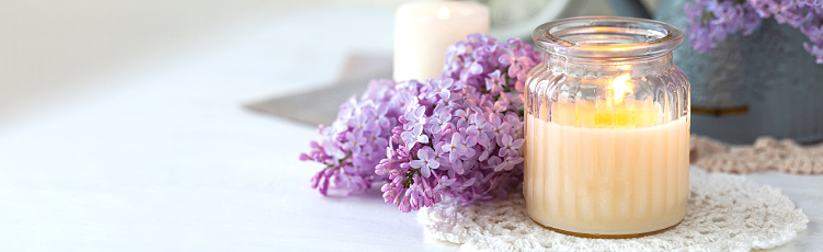 Beautiful composition with fresh violet lilac bouquet in watering and candles. Cozy atmosphere. Greeting card for Saint Valentine's Day, 8 march, Women's day, Mother's day. Banner