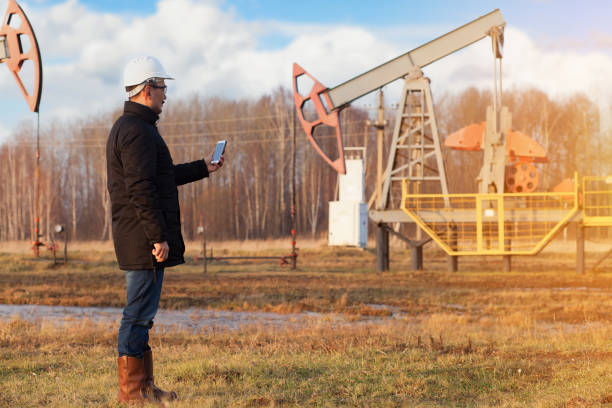 istock A chemical engineer in a white helmet holds a phone in his hands while watching the working oil pumps 1367091758