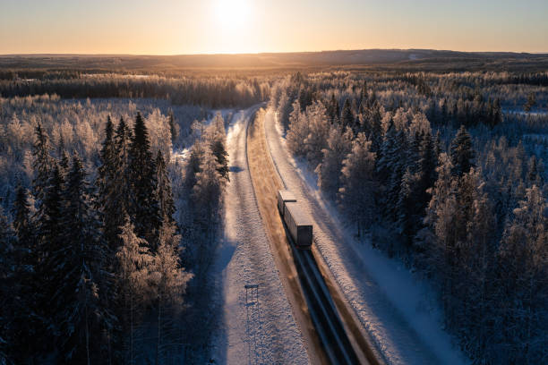 грузовой автомобиль на шоссе в зимнем пейзаже на фоне заката. доставка и транспортировка по северной европе. - aerial view landscape scenics snow стоковые фото и изображения