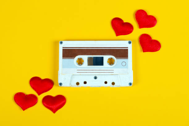 Old Audio Cassette closeup Old Audio Cassette with a Red Hearts on the Yellow Paper Background closeup mix tape heart stock pictures, royalty-free photos & images