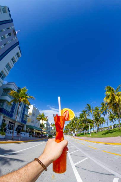 POV Point of view shot of a young travel male enjoying his vacations while drinking a cocktail in front of Ocean Drive, South Beach, Miami Beach, Miami, South Florida, United States of America POV Point of view shot of a young travel male enjoying his vacations while drinking a cocktail in front of Ocean Drive, South Beach, Miami Beach, Miami, South Florida, United States of America.
The picture is in the famous and touristic Art Deco District. Shooting from a personal perspective in an exotic tropical beach travel holidays.
Travel Concept. 1 hotel south beach stock pictures, royalty-free photos & images