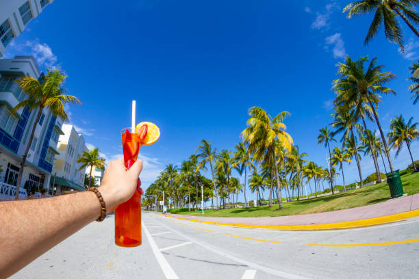 POV Point of view shot of a young travel male enjoying his vacations while drinking a cocktail in front of Ocean Drive, South Beach, Miami Beach, Miami, South Florida, United States of America POV Point of view shot of a young travel male enjoying his vacations while drinking a cocktail in front of Ocean Drive, South Beach, Miami Beach, Miami, South Florida, United States of America.
The picture is in the famous and touristic Art Deco District. Shooting from a personal perspective in an exotic tropical beach travel holidays.
Travel Concept. 1 hotel south beach stock pictures, royalty-free photos & images