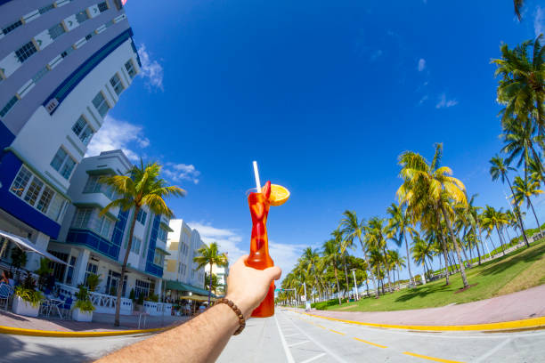 POV Point of view shot of a young travel male enjoying his vacations while drinking a cocktail in front of Ocean Drive, South Beach, Miami Beach, Miami, South Florida, United States of America POV Point of view shot of a young travel male enjoying his vacations while drinking a cocktail in front of Ocean Drive, South Beach, Miami Beach, Miami, South Florida, United States of America.
The picture is in the famous and touristic Art Deco District. Shooting from a personal perspective in an exotic tropical beach travel holidays.
Travel Concept. 1 hotel south beach stock pictures, royalty-free photos & images