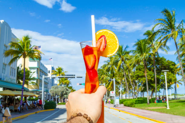 POV Point of view shot of a young travel male enjoying his vacations while drinking a cocktail in front of Ocean Drive, South Beach, Miami Beach, Miami, South Florida, United States of America POV Point of view shot of a young travel male enjoying his vacations while drinking a cocktail in front of Ocean Drive, South Beach, Miami Beach, Miami, South Florida, United States of America.
The picture is in the famous and touristic Art Deco District. Shooting from a personal perspective in an exotic tropical beach travel holidays.
Travel Concept. 1 hotel south beach stock pictures, royalty-free photos & images