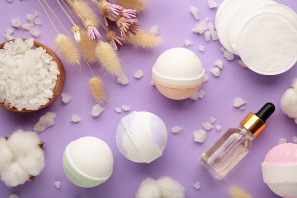 istock Aroma bath bombs in spa composition with dry flowers and salt on purple background. Vertical photo 1367104012