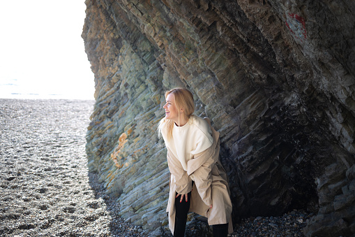 young beautiful woman on the seashore against the background of rocks.