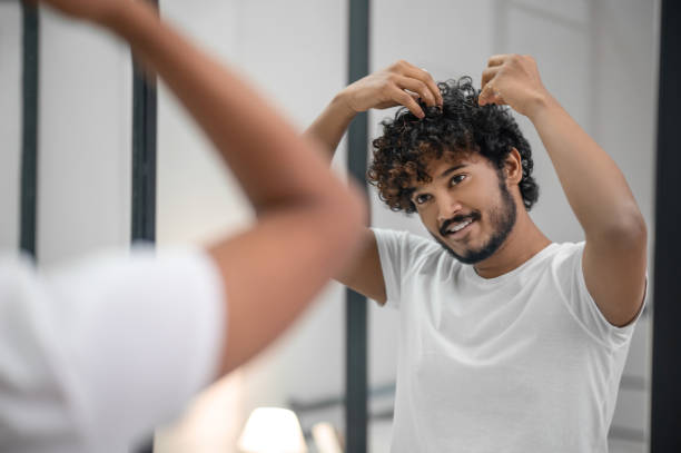 istock Pleased focused guy styling his curly hair with foaming mousse 1367104184