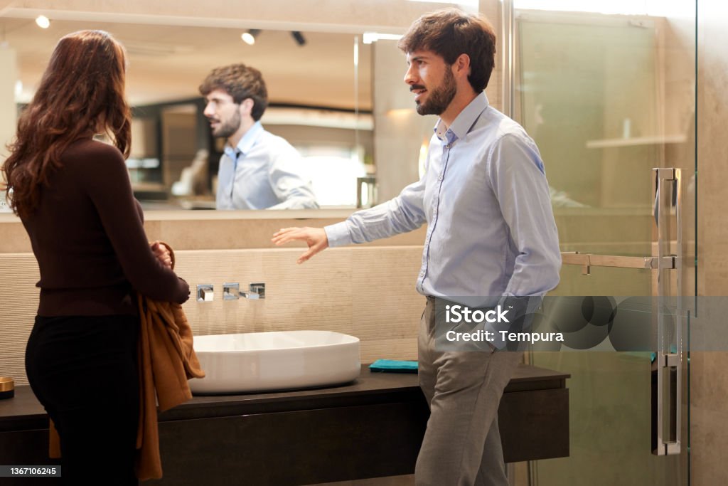 A couple visits a furniture showroom A couple is looking at a bathroom set-up in a showroom. Business Stock Photo