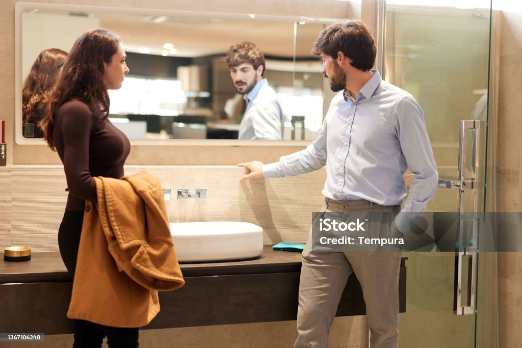 A woman visiting a showroom and choosing a new sink. A sales clerk is showing bathroom equipment to a customer. Bathroom Stock Photo