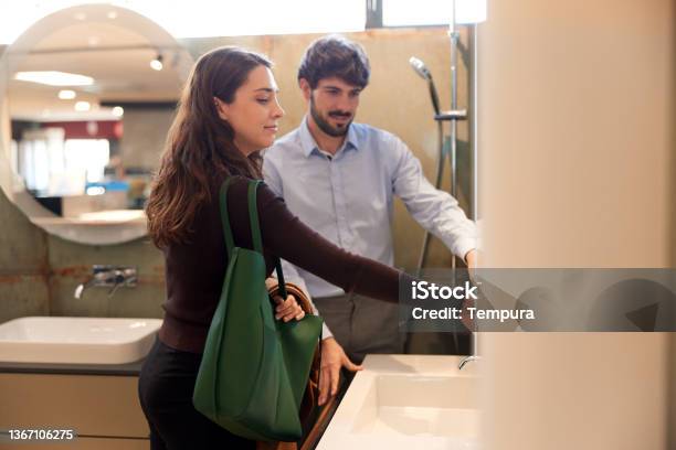 A Couple Is Choosing Faucets For Their New Home Stock Photo - Download Image Now - Bathroom, Color Image, Exhibitor