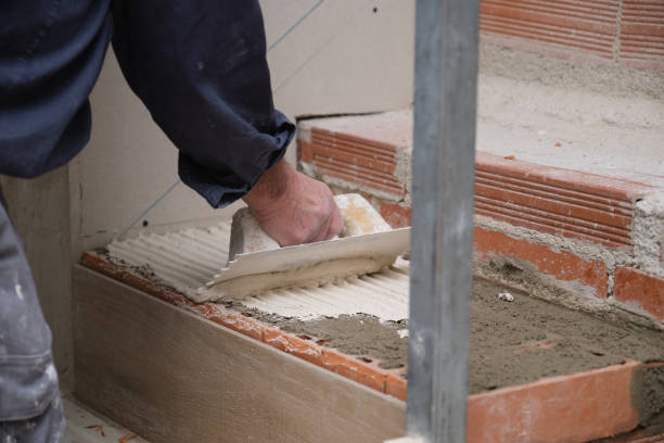 istock Unrecognizable bricklayer using a notched trowel to build a staircase in a home. 1367107610