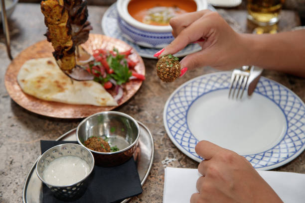 istock Hand holding falafel ball at the table in ethnic restaurant 1367109034