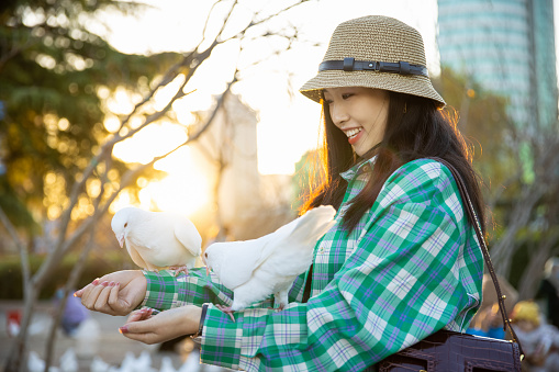 Young women feeding pigeons in park