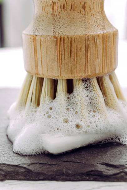 Close up view of solid dish washing soap, covered with foam on black stone cutting board. Zero waste lifestyle. Foamy kitchen cleaning sisal bamboo round dish brush. Minimalist background. vista de cerca del jabón sólido para lavar platos, cubierto con espuma sobre tabla de cortar de piedra negra. estilo de vida cero residuos. cepillo de plato redondo de bambú de bambú de limpieza espumoso y espumoso de cocina. fondo minimalista.