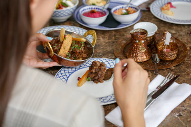 istock Taking meat specialty from copper bowl with spoon, dinner party at restaurant table 1367109092