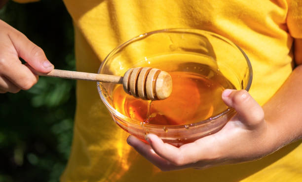 istock child eats honey in the garden. Nature 1367112098
