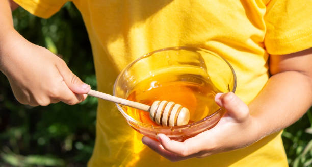 istock child eats honey in the garden. Nature 1367112120