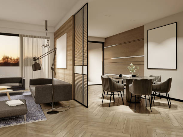 Evening interior dining room with a round dining table and black soft chairs and white walls with a glass partition and a large painting.