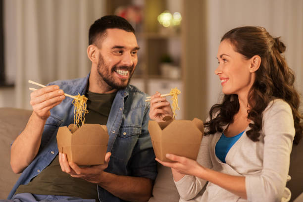 glückliches paar essen zum ende nudeln zu hause - eating men food chopsticks stock-fotos und bilder