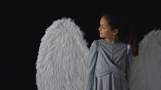 Studio shot portrait curious girl wearing angel wings