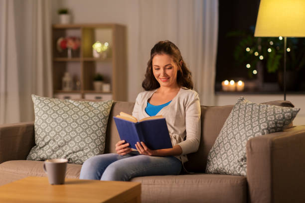 istock young woman reading book at home in evening 1367113924