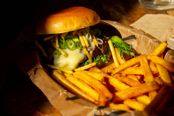 istock Cheeseburger with fries in paper on table 1367115060