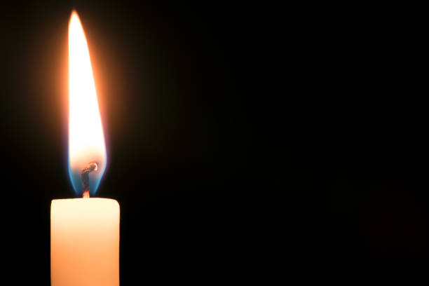 istock Closeup burning wax candle against black background 1367116314