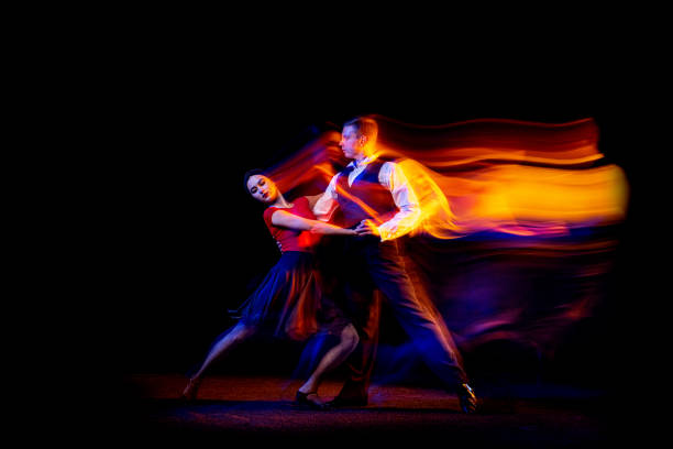 dynamic portrait of young ballroom dancers dancing argentine tango isolated on dark background with neon mixed light. - tangoing imagens e fotografias de stock