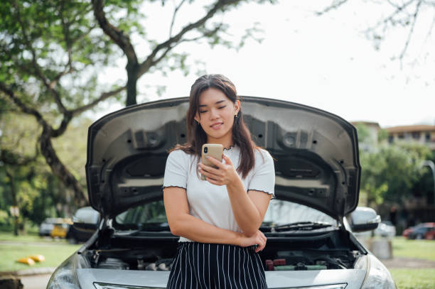 giovane donna asiatica aspetta assistenza vicino alla sua auto in panne sul ciglio della strada - car insurance women driving foto e immagini stock