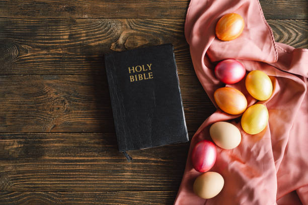 traditional holiday symbol. multicolored easter eggs and holy bible on a wooden background. - easter egg religion cross spirituality imagens e fotografias de stock