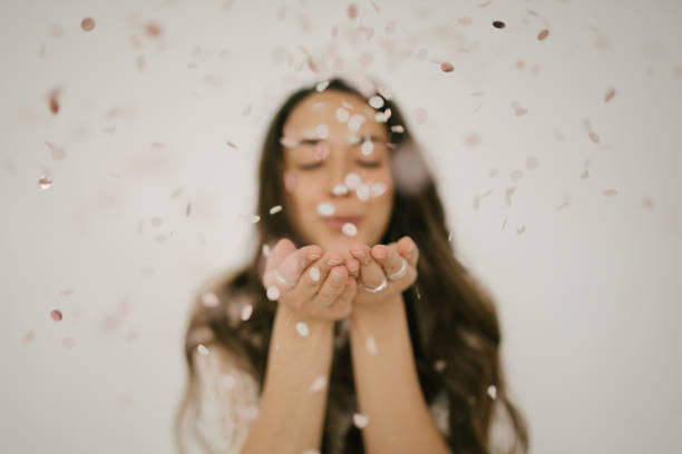 istock Young woman throwing paper confetti on white background. 1367121977