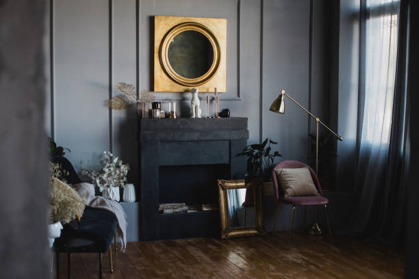 istock Modern interior with big mirror in golden frame hanging above black decorative fireplace. 1367123403