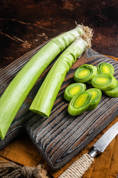 istock Sliced Green Leeks on wooden cutting board. Dark background. Top view 1367123659