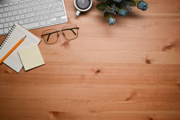istock Above view keyboard, glasses, coffee cup and notebook on wooden table. 1367123698
