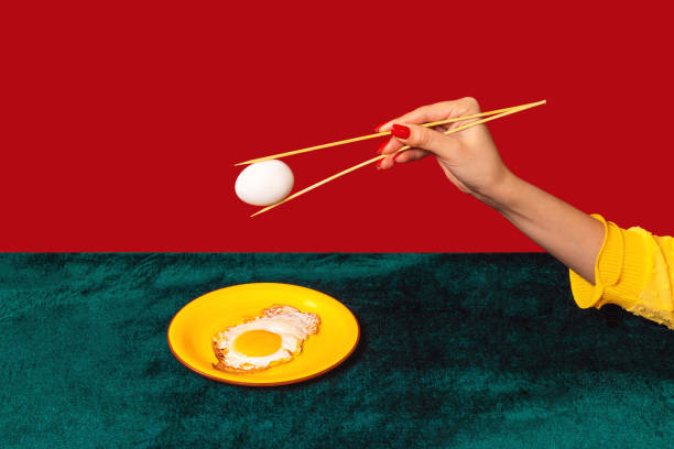 istock Woman's hand tasting fried eggs with chopsticks isolated on green and red background. Vintage, retro style interior. Food pop art photography. 1367125820