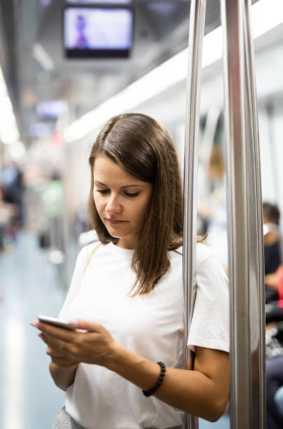 istock Woman using phone in subway car 1367125987