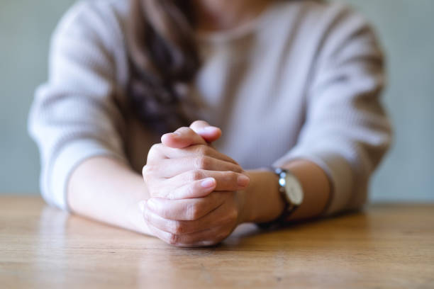 istock Closeup image of a woman with folded hands on knees while thinking, waiting, praying or making decision 1367126131
