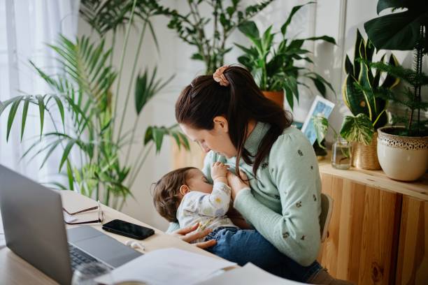 母は仕事をし、オフィスで彼女の赤ちゃんを母乳で育てる - dairy product audio ストックフォトと画像