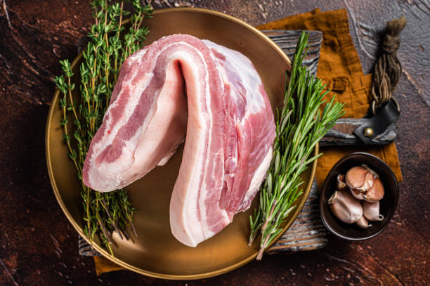Farm fresh Pork belly, raw meat in a plate with spices. Dark background. Top view Farm fresh Pork belly, raw meat in a plate with spices. Dark background. Top view. berkshire pig stock pictures, royalty-free photos & images