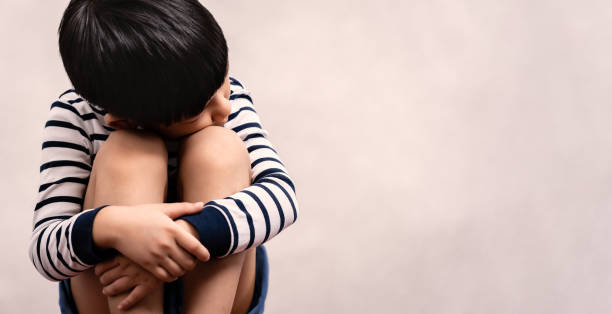 Little Asian boy child sit, hug knees and look away, feeling sad, stressed, depressed and lonely. Little Asian boy child sit, hug knees and look away, feeling sad, stressed, depressed and lonely. Domestic violence, Autism, Bipolar disorder and mental illness concept. face down stock pictures, royalty-free photos & images